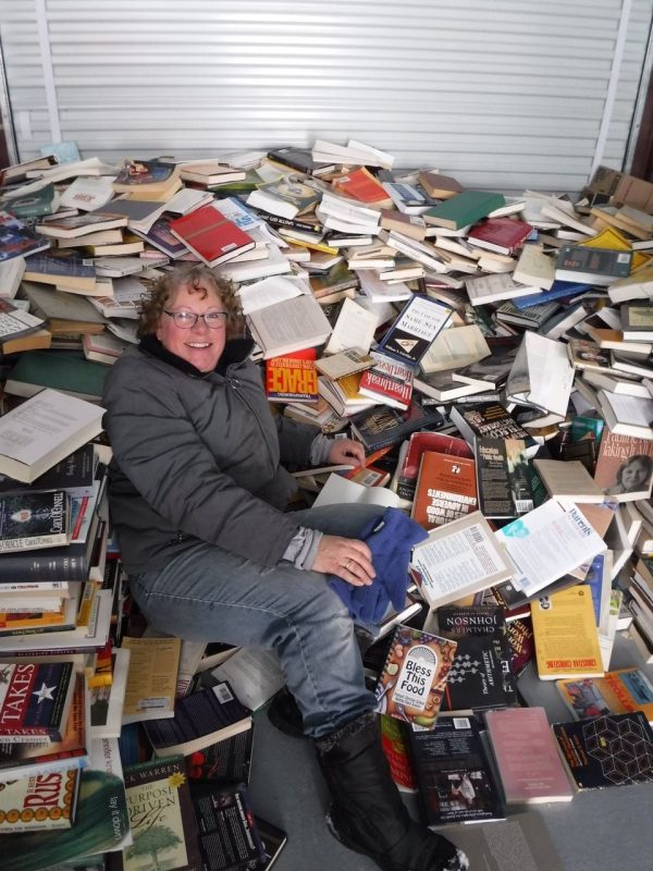 Volunteer laying in a giant pile of donated books